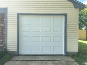 A plain white builder-grade steel garage door on a home